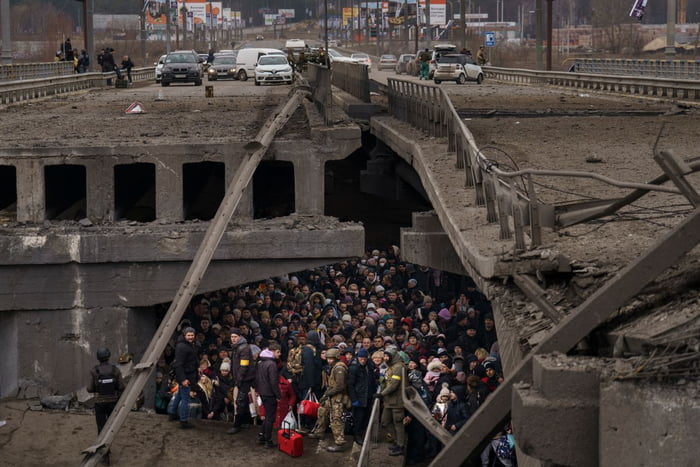Ukrainians crowd under a destroyed bridge as they try to fle
