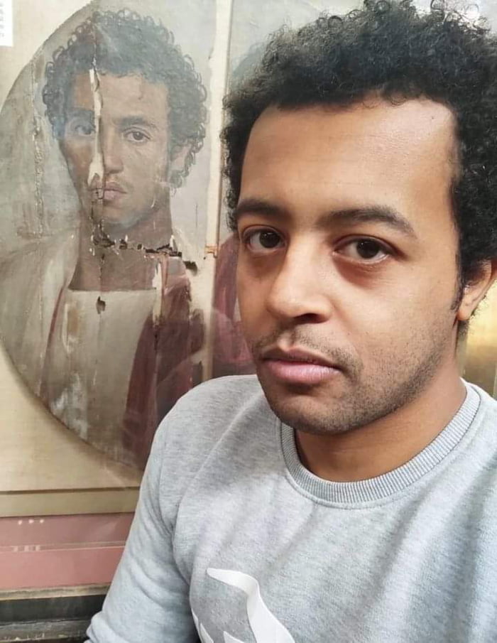 Egyptian man in front of a 2000-year-old painting made by a 